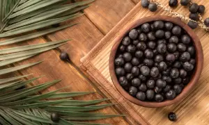Misternie ułożone owoce acai w drewnianej misce, otoczone liśćmi palmowymi. Zastanawiasz się acai co to? To egzotyczne jagody pełne zdrowia!