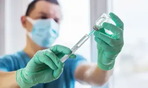 Medyk w masce i rękawiczkach przygotowuje zastrzyk. To ważny krok w kierunku szczepienia na tężec, chroniącego przed groźną chorobą.