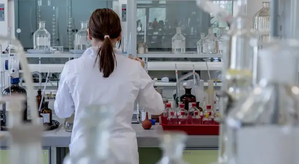 Naukowczyni w białym fartuchu analizuje próbki, badając wskaźnik anizocytozy erytrocytów wśród laboratoryjnego sprzętu.