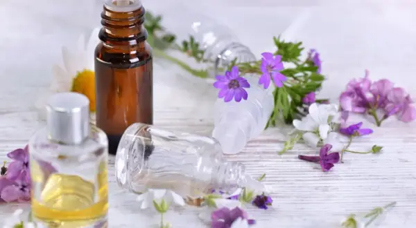 Aromaterapia: amol na co pomaga? Butelki z olejkami i kwiaty sugerują relaks i ukojenie.